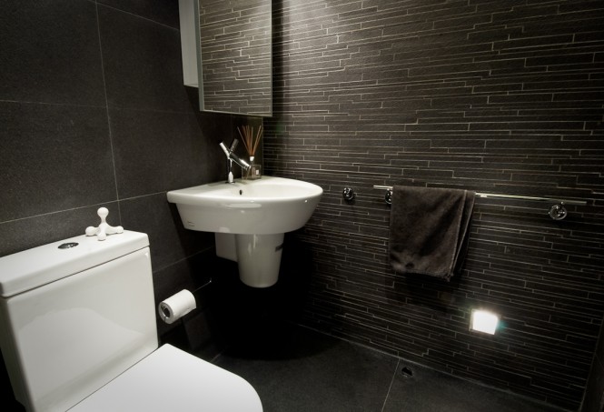 The bathroom is decorated in stark contrast to the warm wood, with cool anthracite floor, slate feature tiles, and grey veined marble walls.